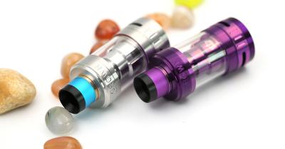 Two multicolored vaping cartridges with pebbles around them on a white background
