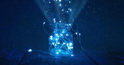 Blue Christams lights on a string and partially in a jar with a mystic background